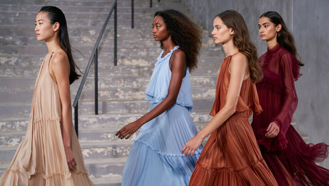 Four women in flowing dresses walking down a set of stairs.